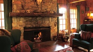 A cozy room with a stone fireplace, wooden walls, and a comfortable seating area. - Beautiful Lake Burton Compound - Pet Friendly (Clarkesville)