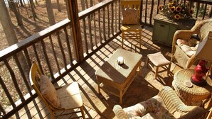 A sunlit outdoor deck with wicker furniture, a small table, and a chair. - Beautiful Lake Burton Compound - Pet Friendly (Clarkesville)