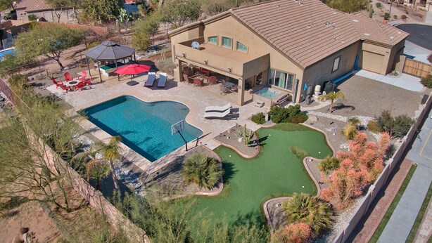 Ein Wohnobjekt mit Schwimmbad, Terrassenmöbeln und einem kleinen Putting Green.