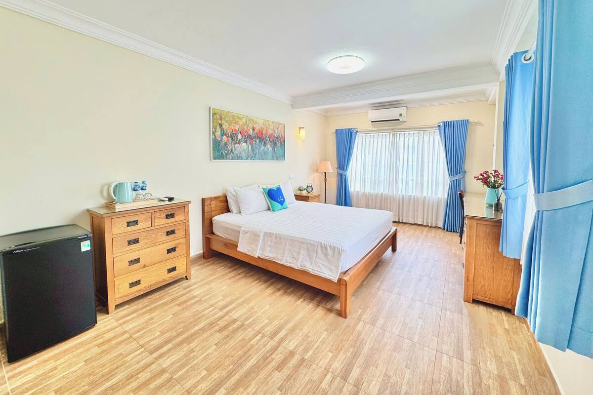 Ein Schlafzimmer mit einem Bett, einem Holzschrank und einem kleinen Kühlschrank.
