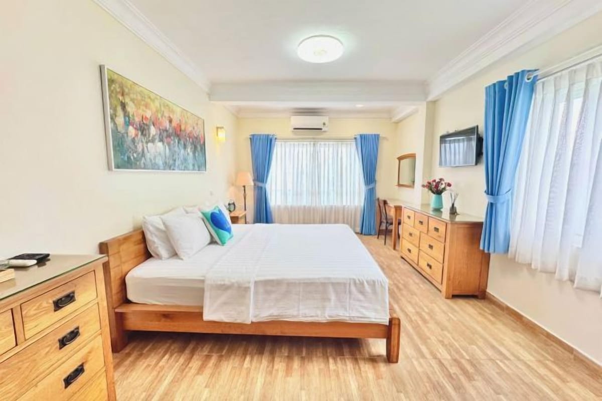 Un dormitorio con una cama de madera, un aparador, un escritorio y un cuadro en la pared.