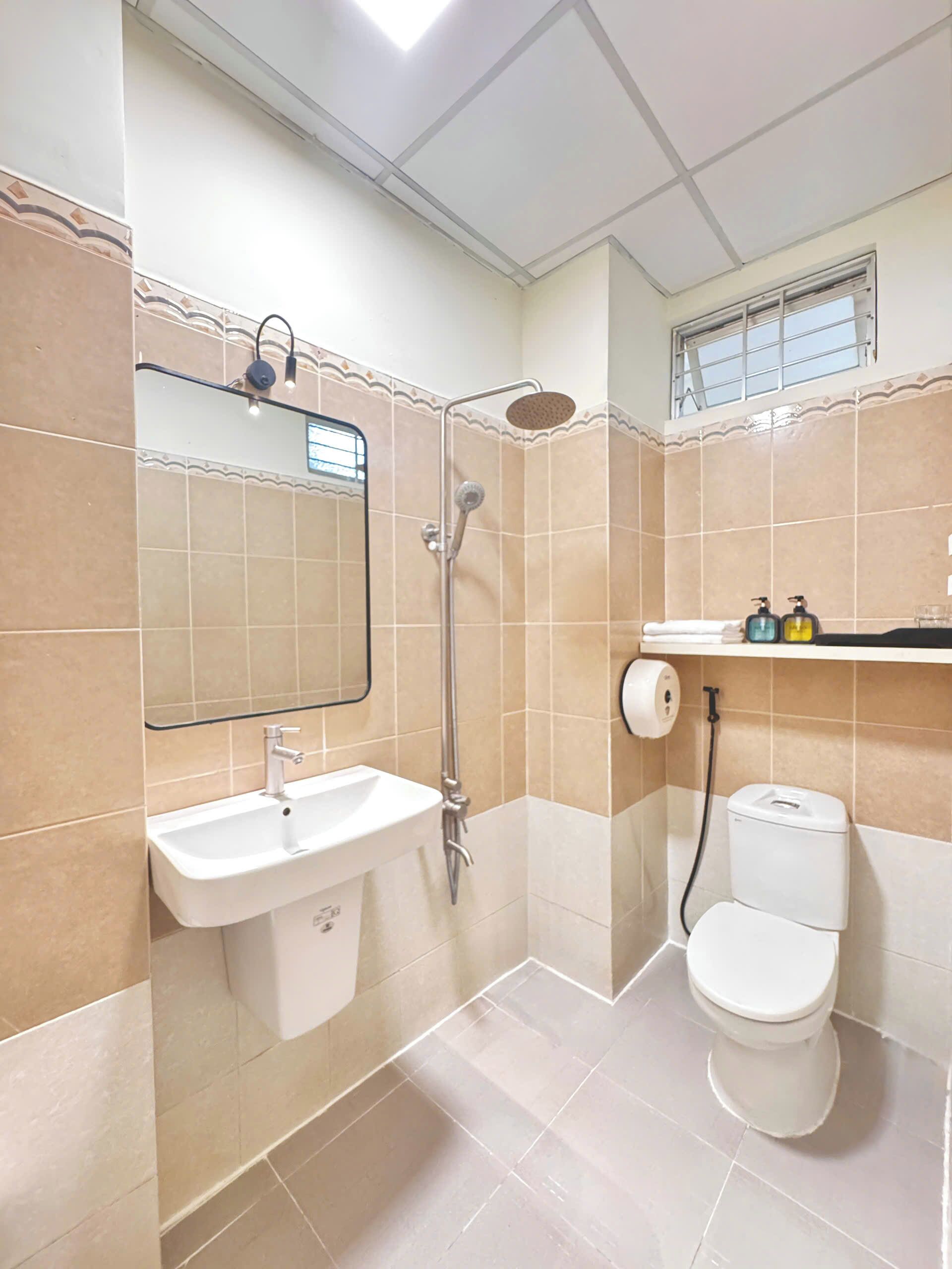 Une salle de bain équipée d’un lavabo, d’un miroir, d’une douche, de toilettes et d’une fenêtre.