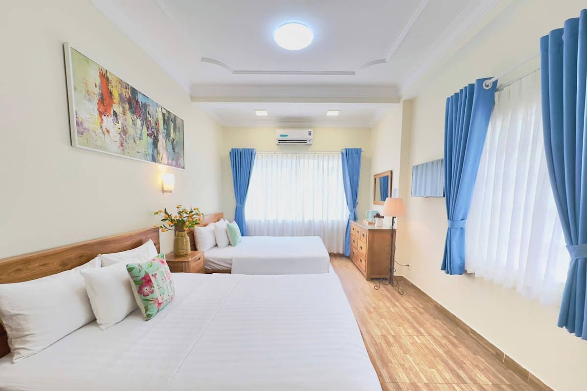 Ein Hotelzimmer mit zwei Betten, Holzboden, Schreibtisch mit Lampe und einem Bild an der Wand.