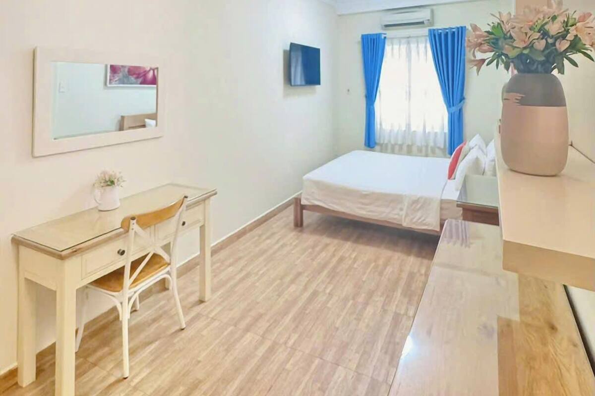 Ein Schlafzimmer mit Bett, Schreibtisch, Stuhl, Spiegel, Fernseher und einer Zimmerpflanze.