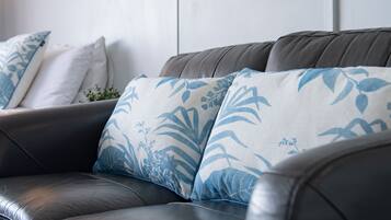 Een donkerbruine leren bank met kussens met een blauw-wit patroon.
