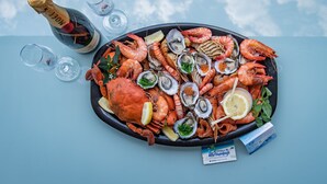 A seafood platter with a bottle of champagne and glasses on a table. - Ocean Views 49 (Airlie Beach)