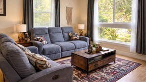 A living room with a grey sofa, a coffee table, and two lamps. - A cabin with beautiful mountain views and outdoor lounge (Dunsmuir)