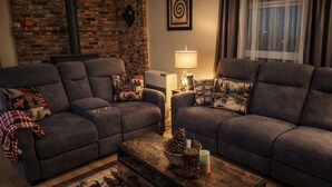 A cozy living room with two grey sofas, a wooden coffee table, and a fireplace. - A cabin with beautiful mountain views and outdoor lounge (Dunsmuir)
