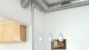 Cocina compacta con armarios de madera, encimera de granito, una banca y luminarias colgantes.