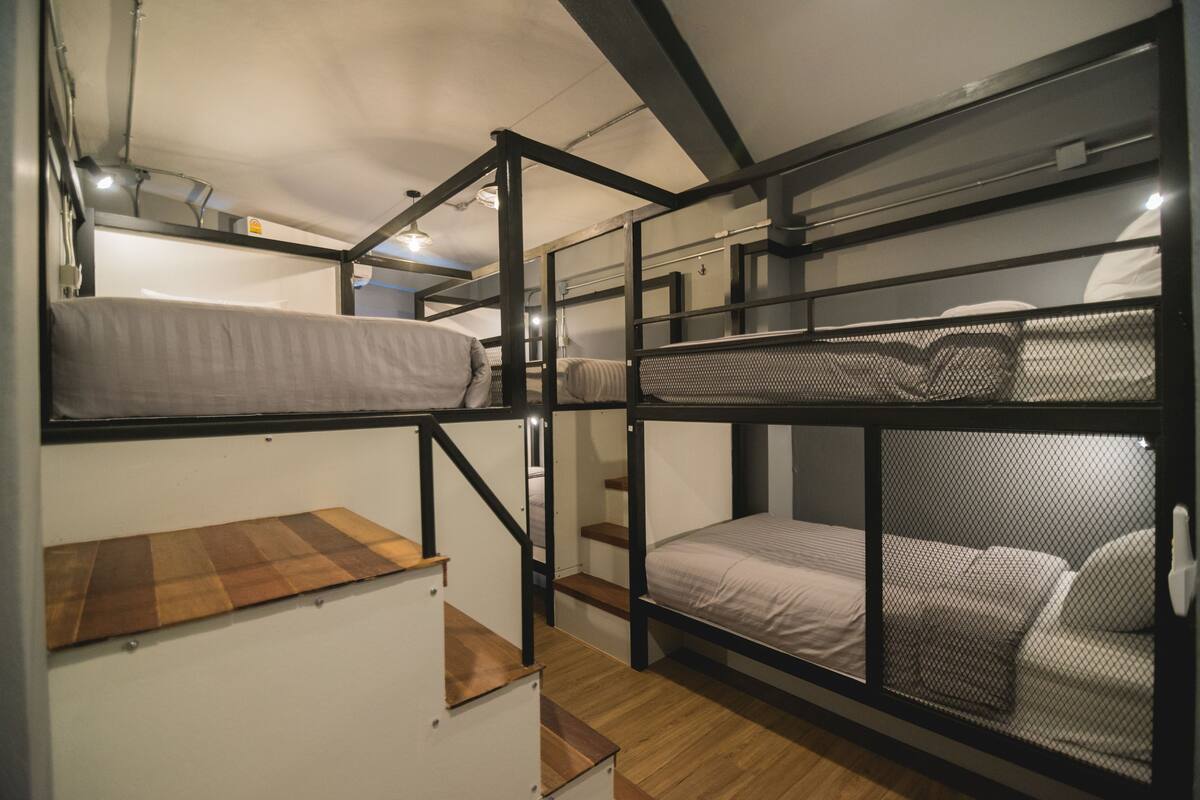 A bunk bed room with a wooden ladder and a small wooden platform.