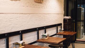 A restaurant interior with wooden tables and chairs, pendant lighting, and wall-mounted decor.
