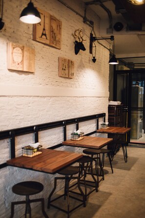 Interior de restaurante con mesas y sillas de madera, iluminación colgante y adornos en la pared.