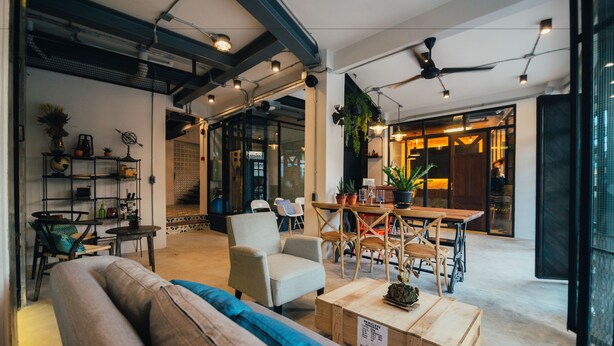 Ein modernes Interieur mit einer Couch, Sesseln, einem Holztisch und einem Essbereich mit Tisch und Stühlen.