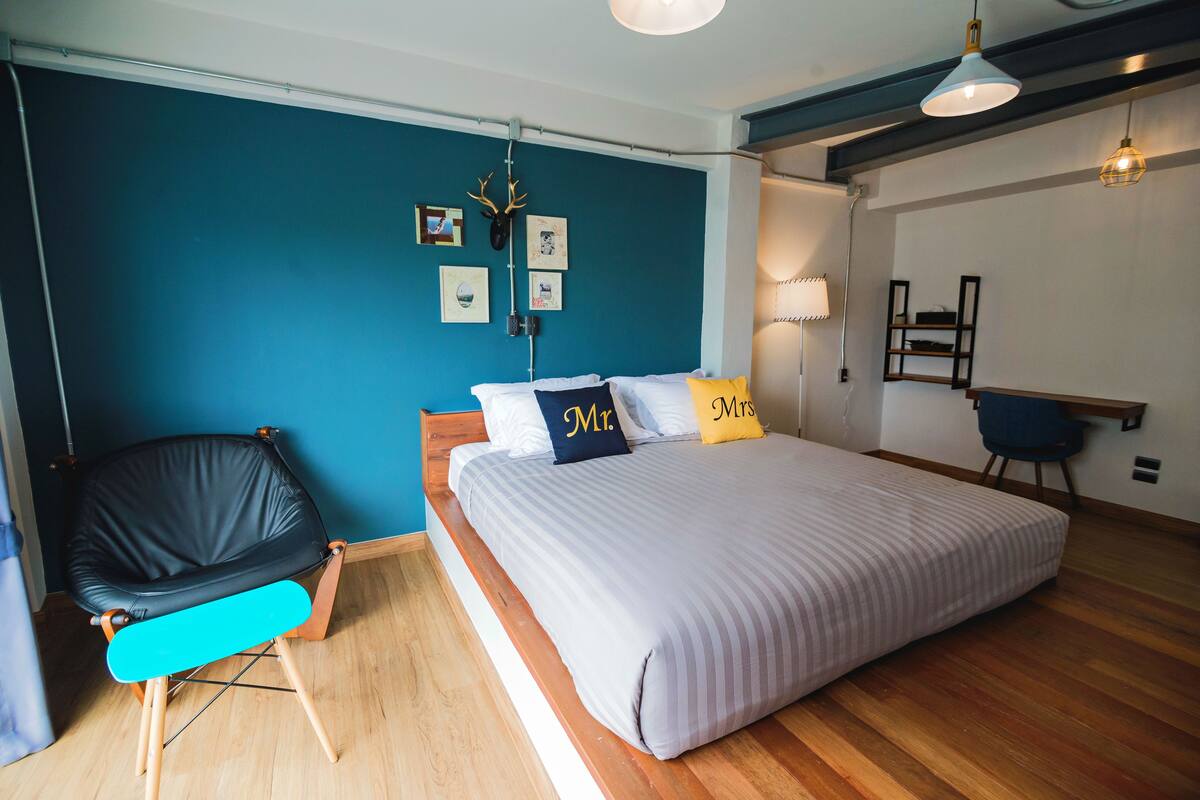 A bedroom with a bed, a chair, and a desk.