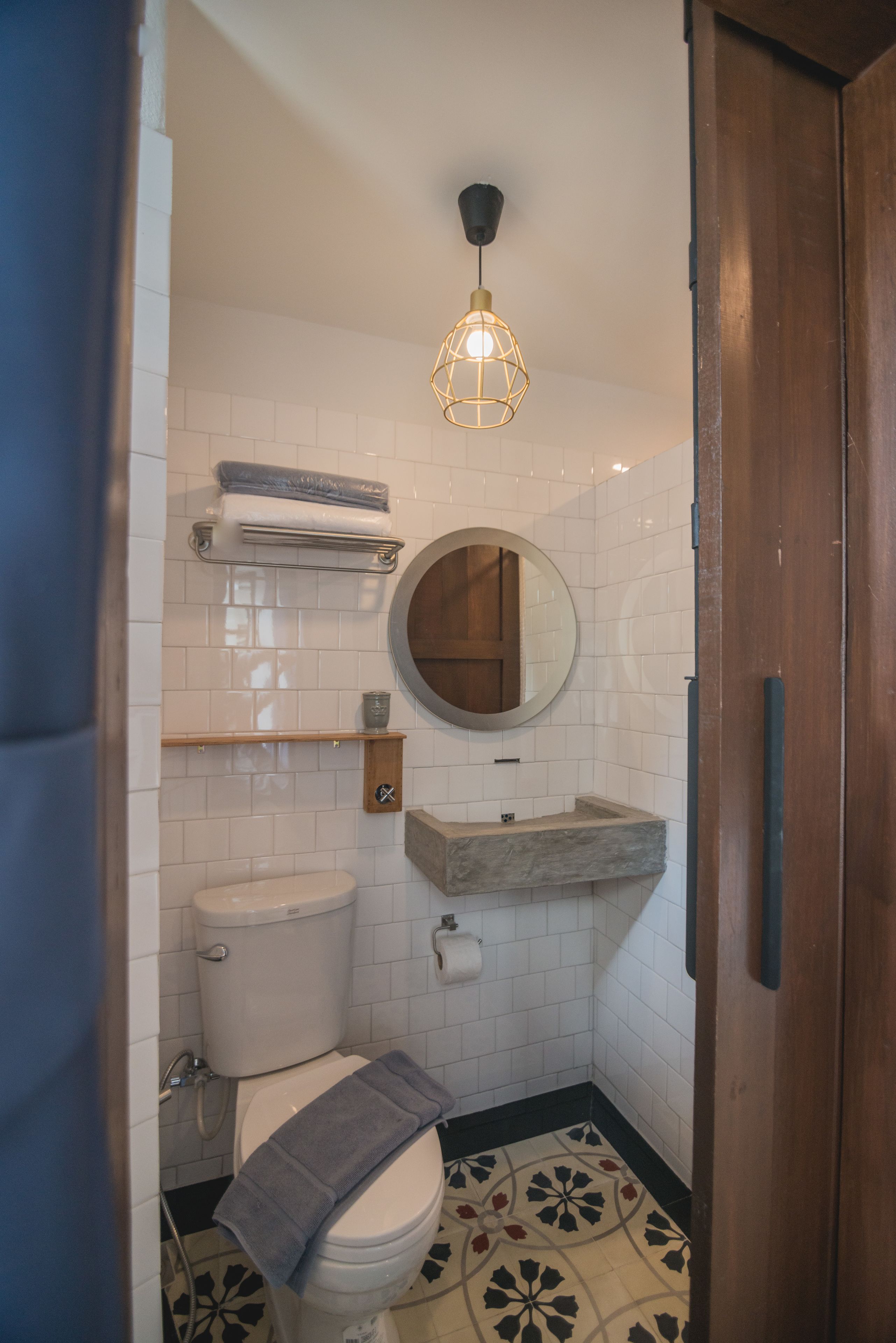 A compact bathroom with a toilet, a sink, a towel rack, and a mirror.