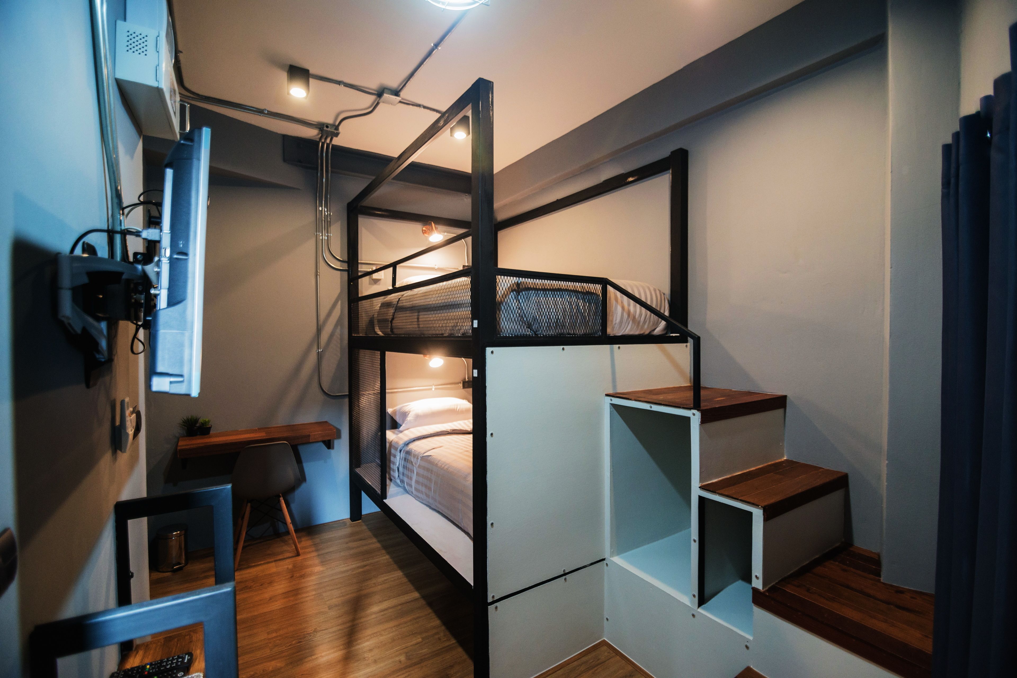 Une petite pièce comprenant un lit superposé, un bureau avec une chaise et une petite fenêtre.