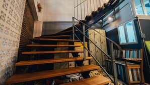 Eine Treppe mit Holzboden und Metallgeländern, die zu einer Zwischenebene mit Fenster und Stuhl führt.
