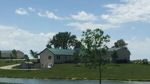 A residential area with a grassy field, a small body of water, and houses with green roofs. - Looking for a cozy getaway? This country property is perfect!  (Weldon)