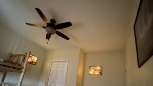 A bedroom with a ceiling fan, a door, a light fixture, and a bed with a patterned bedspread. - Looking for a cozy getaway? This country property is perfect!  (Weldon)