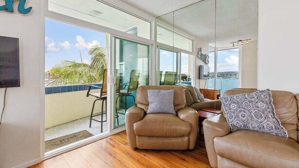 A spacious living area with a large sliding glass door leading to a balcony, leather sofas, and a view of the sea. - BAYFRONT! AUGUST 8 - 10 OPEN AMAZING VIEWS & LOCATION WALK TO FOOD, SHOPS, OCEAN (San Diego)