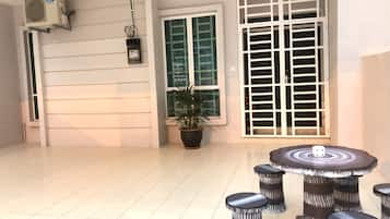 A spacious room with a tiled floor, a potted plant, a large window with a view, and a table with stools.