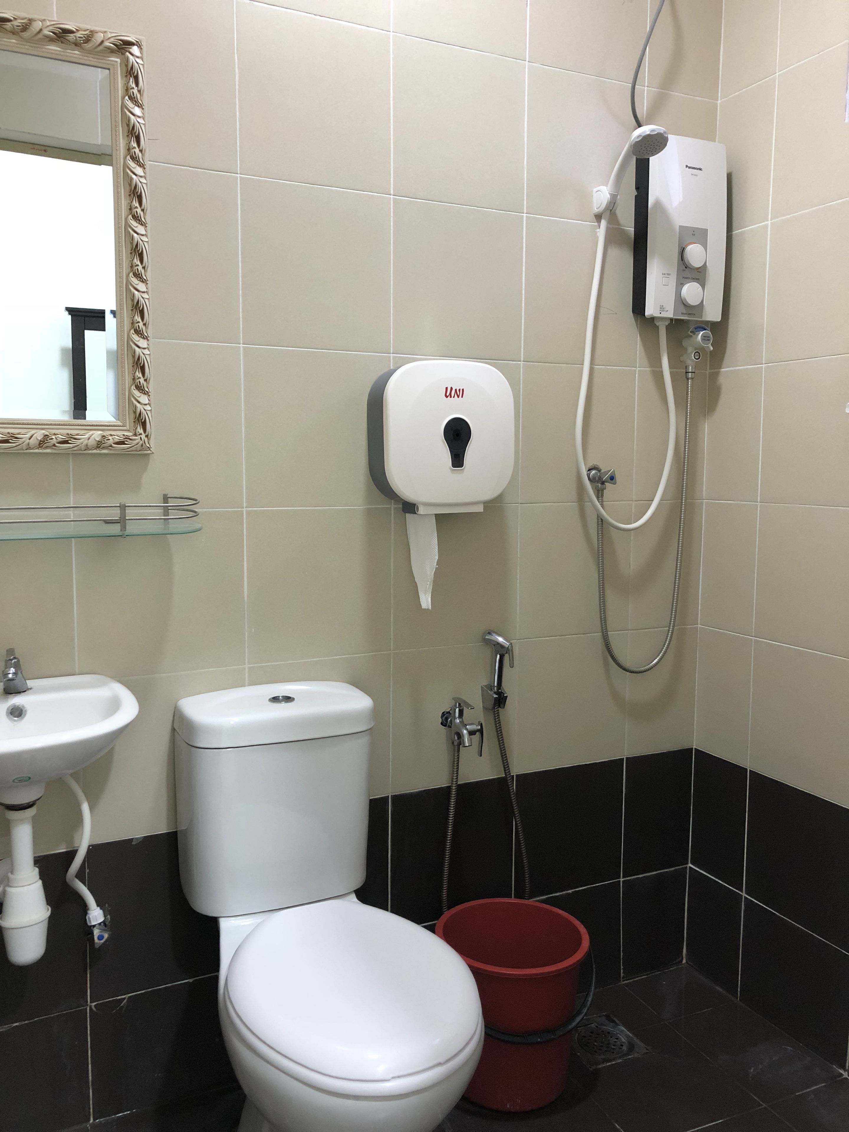 A bathroom with a toilet, sink, and a hand dryer.