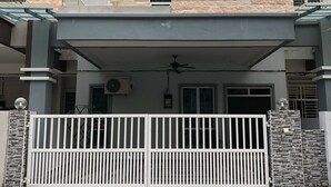 A modern two-story house with a covered front porch, stone facade, and a gated entrance. - Langkawi Shell Out Villa (Langkawi)