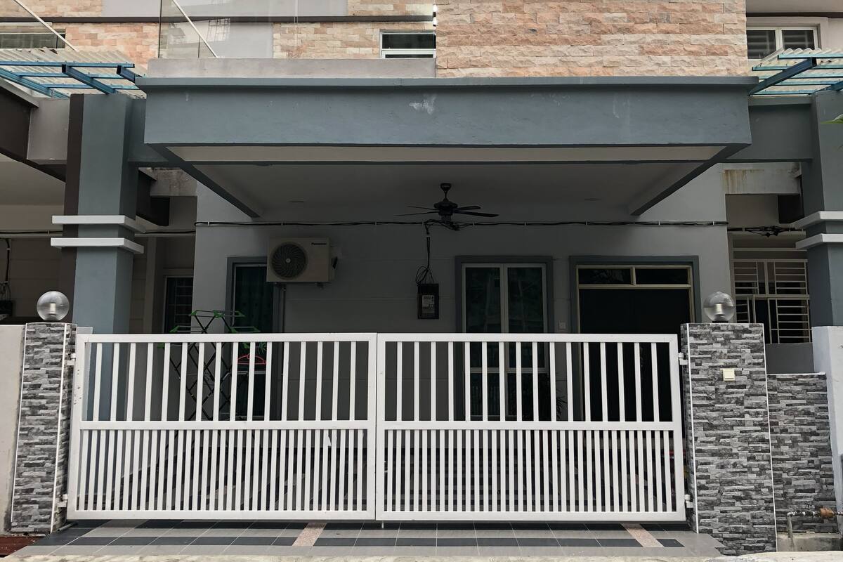 A modern two-story house with a covered front porch, stone facade, and a gated entrance.