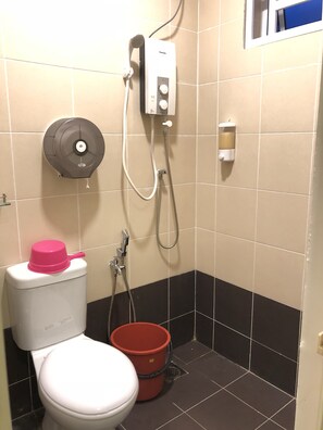 A small bathroom with a toilet, a shower, and a soap dispenser.