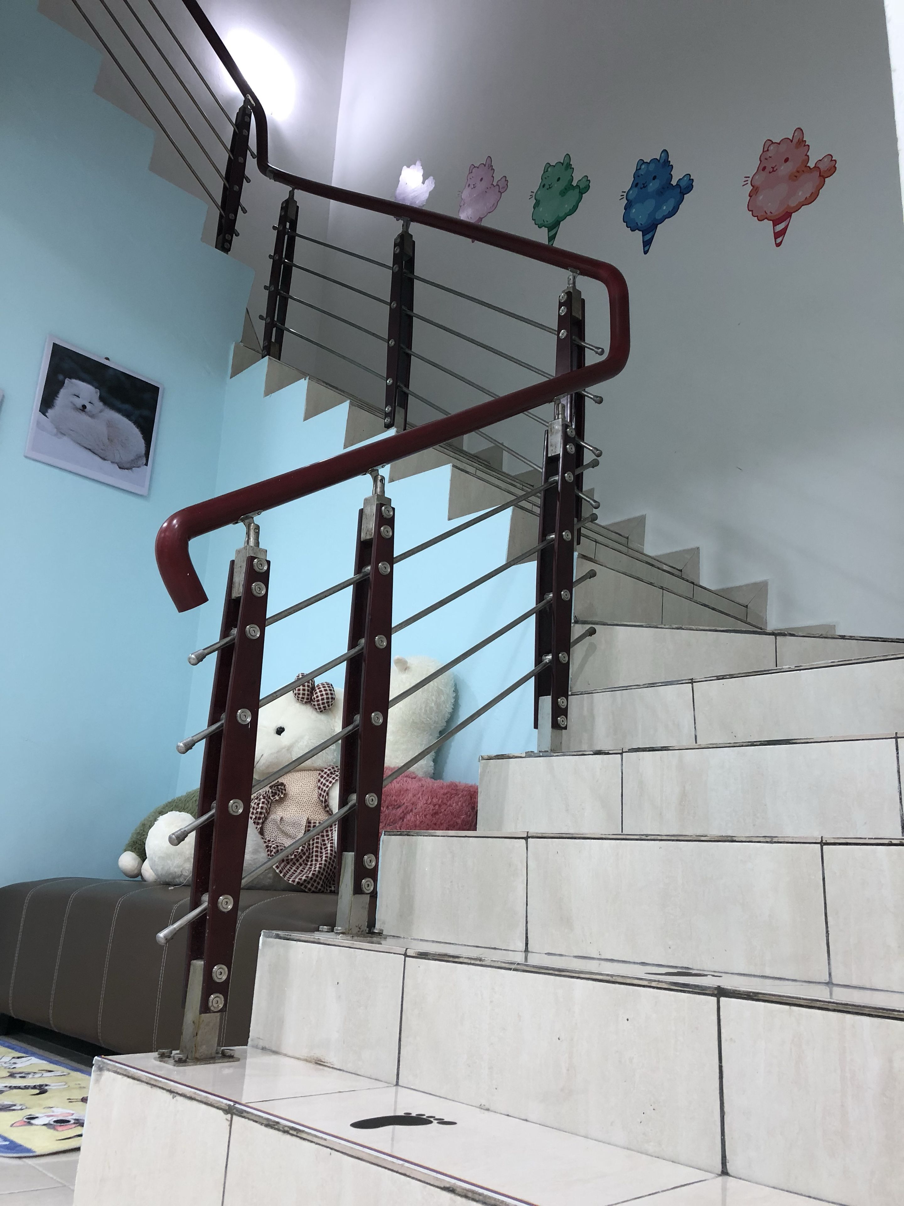 A staircase with a handrail, a wall-mounted picture, and a tiled floor.