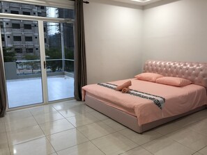 A bedroom with a bed, a sliding glass door leading to a balcony, and a view of a building under construction.