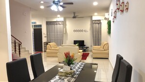A modern living room with a dining table, sofas, and a TV. - Langkawi Shell Out Villa (Langkawi)
