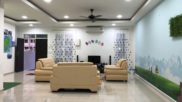 A modern living room with two beige sofas, a flat-screen TV, and a ceiling fan. - Langkawi Shell Out Villa (Langkawi)
