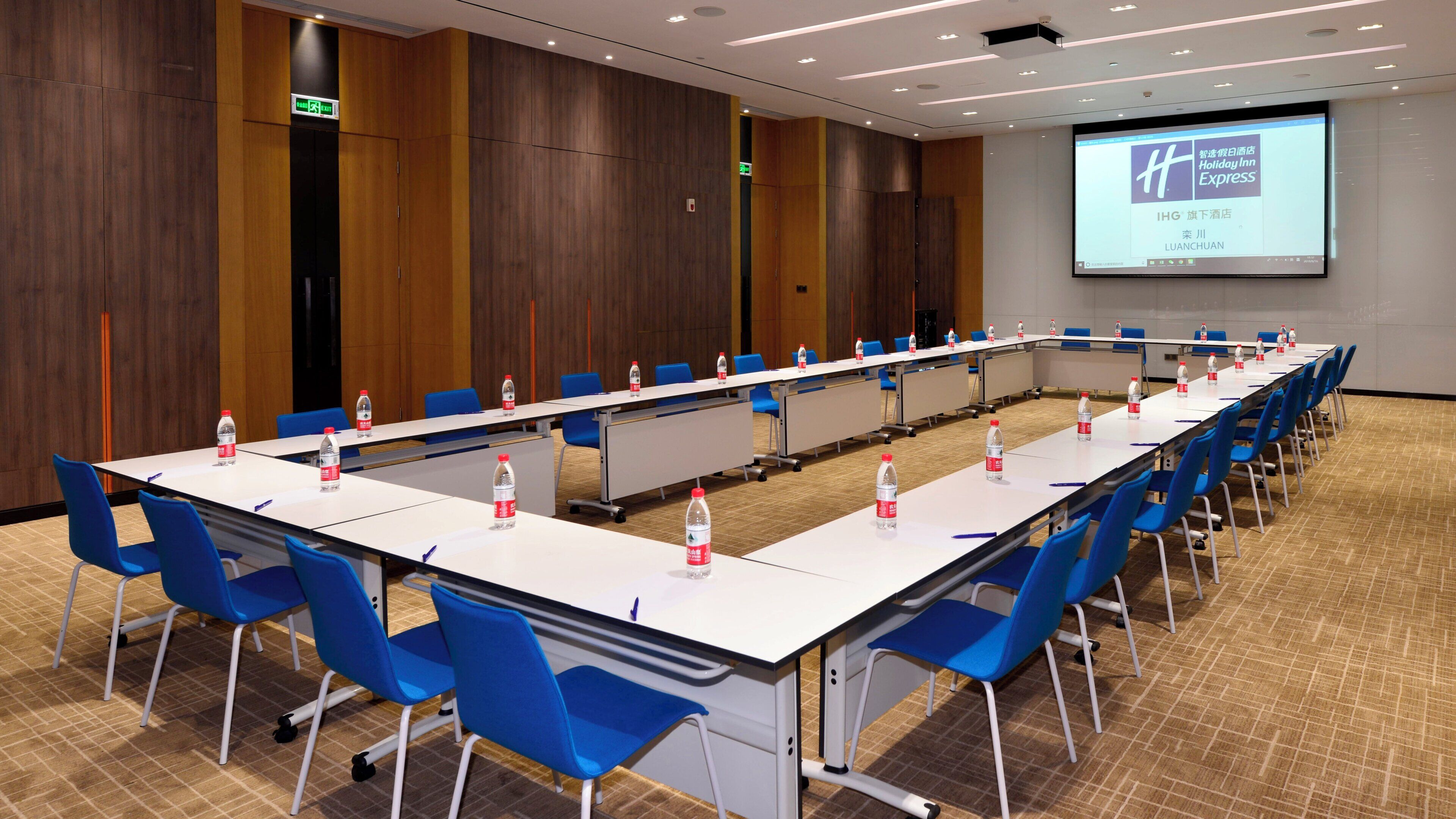 A conference room with a long table, blue chairs, and water bottles.