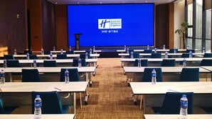 A conference room with rows of tables, water bottles, and a large screen displaying the Holiday Inn Express logo. - Holiday Inn Express Luanchuan by IHG (Luoyang)