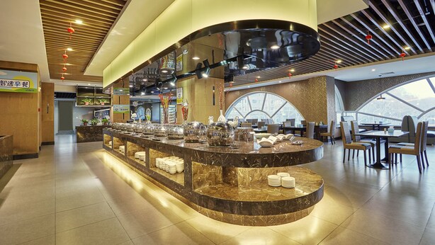 A modern restaurant with a central counter, seating area, and large windows.