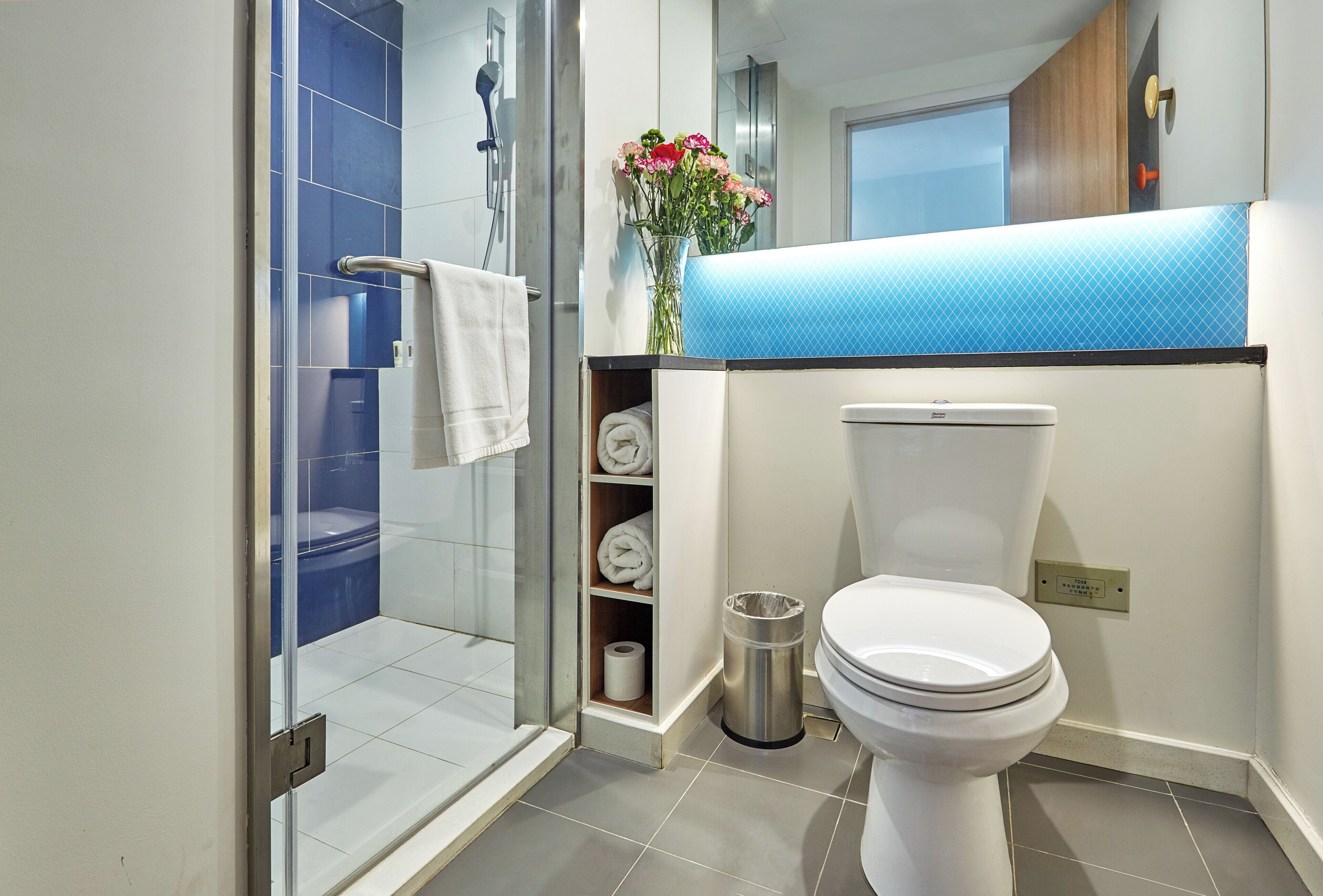 Un bagno moderno con cabina doccia in vetro, un water e un lavabo con piano d'appoggio blu.