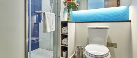 A modern bathroom with a glass shower enclosure, a toilet, and a sink with a blue countertop.