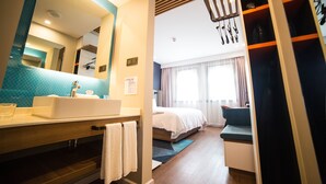 A modern hotel bathroom with a large mirror, sink, and towel rack.