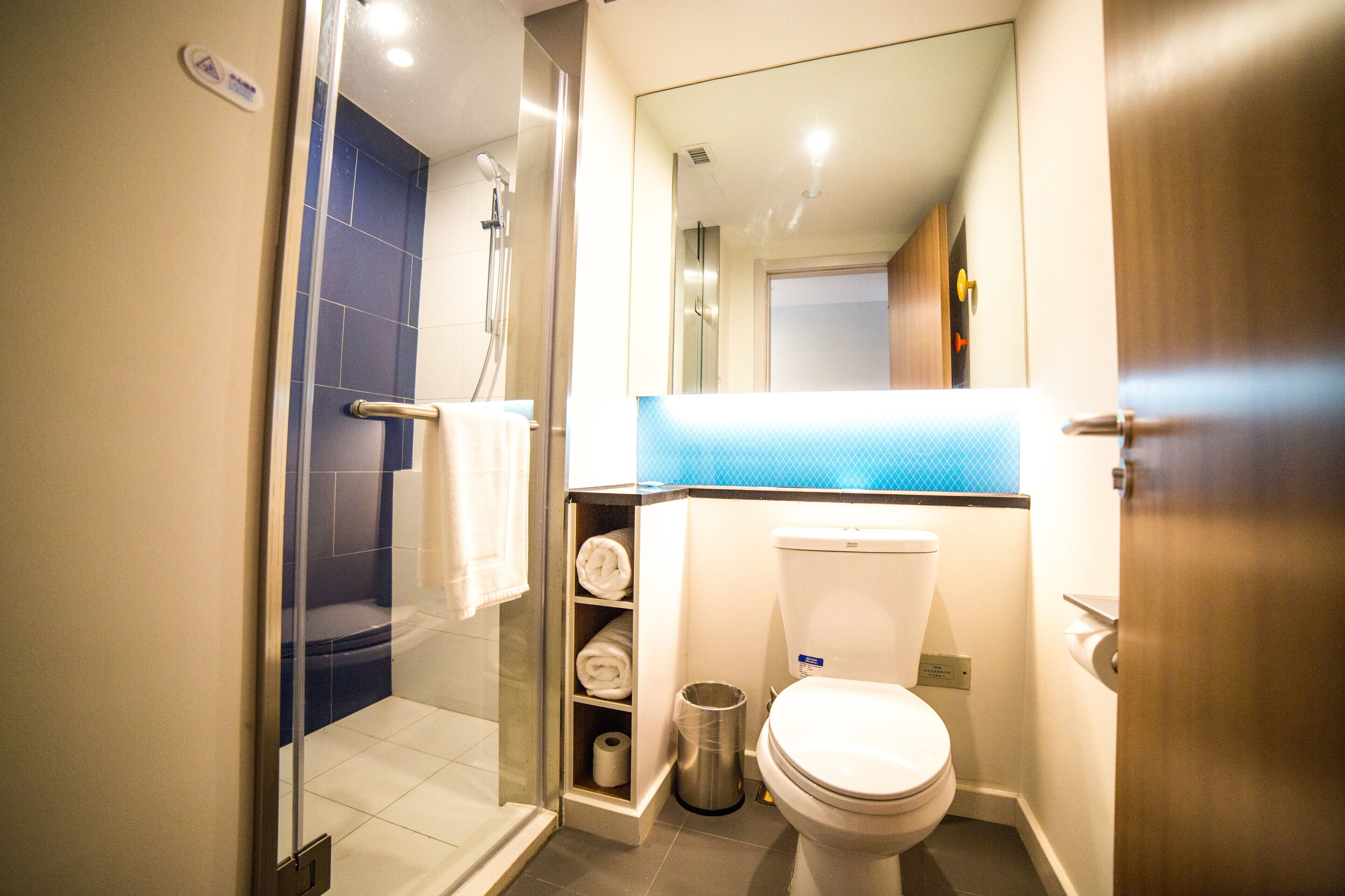 A bathroom with a glass shower enclosure, a toilet, a sink, and a towel rack.