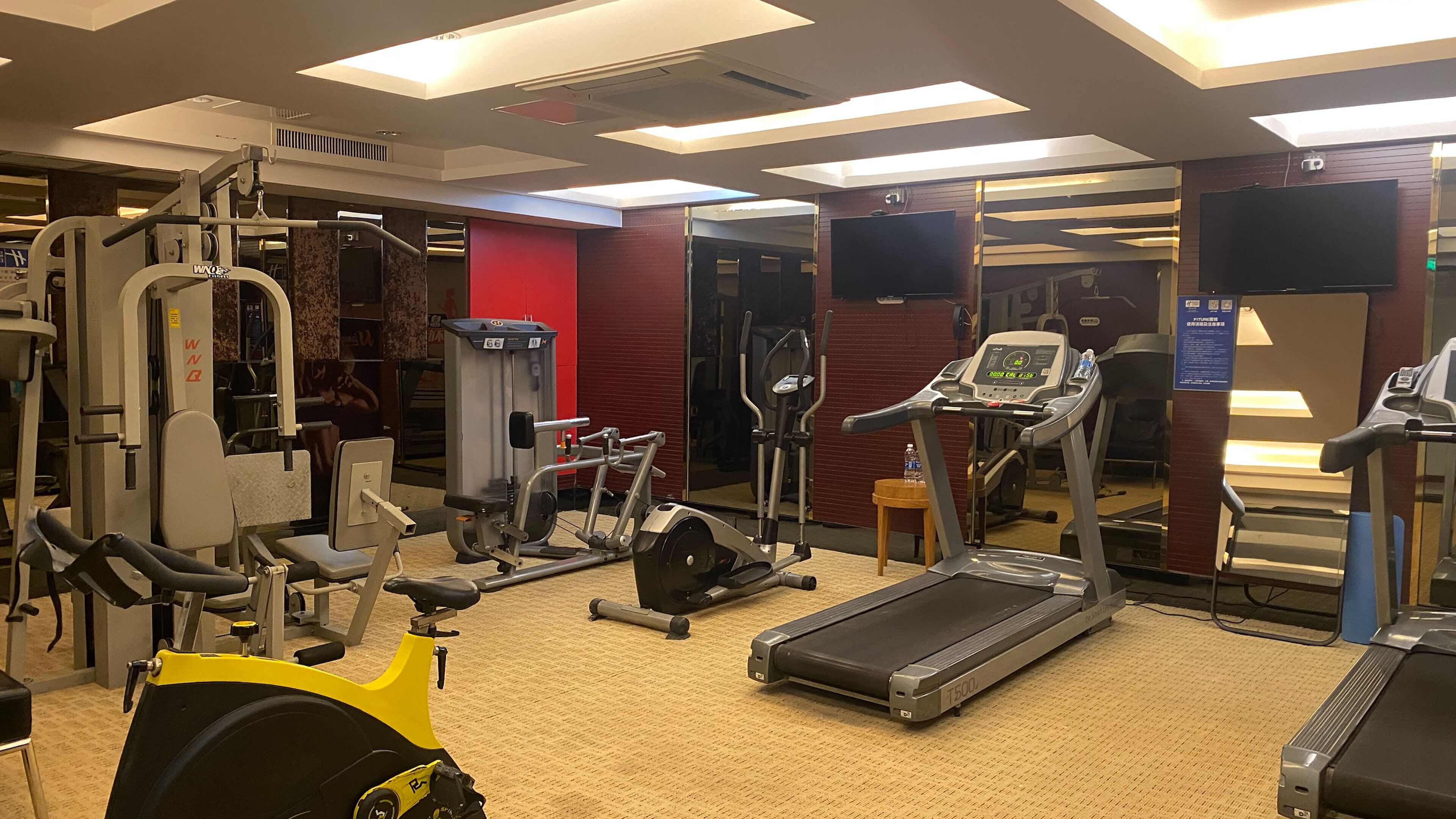 A gym with various exercise equipment including treadmills, an elliptical, and weight machines.
