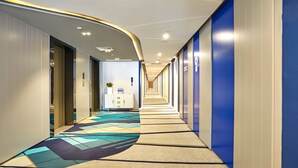 A hotel corridor with a patterned carpet, a reception desk, and a blue accent wall.