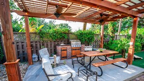A covered patio area with a grill, seating, and a table. - Inn The Heights - Apt. 9 (Tampa)