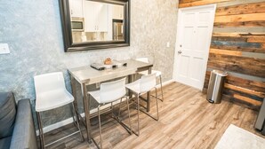 A modern kitchen with a wooden wall panel, a large mirror, and a stainless steel trash can. - Inn The Heights - Apt. 9 (Tampa)