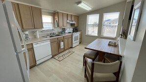 A kitchen with wooden cabinets, a white dishwasher, a stove, and a dining table with chairs.