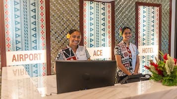 Un comptoir d’accueil avec des panneaux indiquant « AÉROPORT » et le nom de l’hôtel, « ACE ».