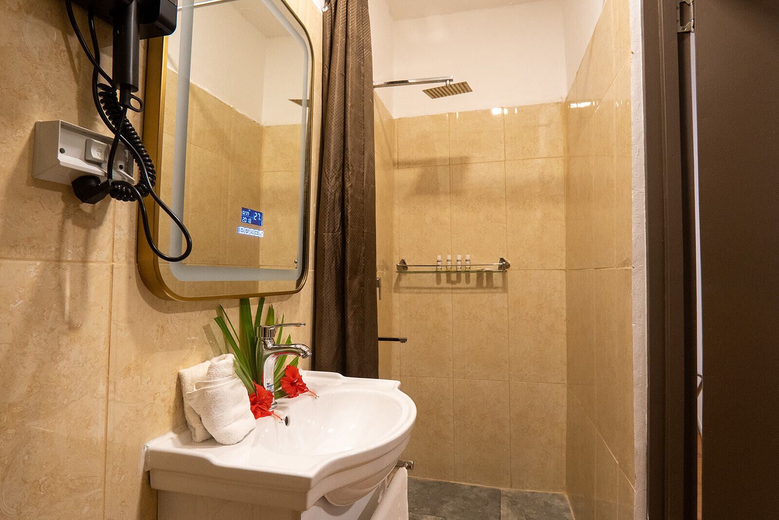 Un baño con lavamanos, espejo, ducha y artículos de aseo.