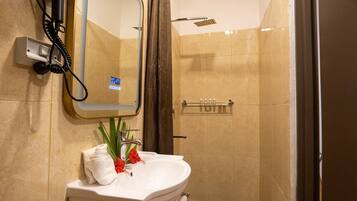 Un baño con lavamanos, espejo, ducha y artículos de aseo.