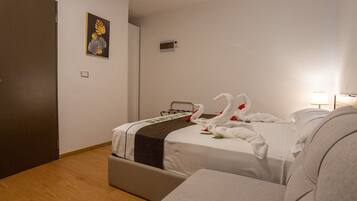 Habitación de hotel con una cama, una mesita de noche, una lámpara y un enchufe en la pared.