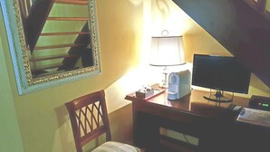 Um quarto pequeno com uma escrivaninha, uma cadeira, um abajur, um computador e um espelho.